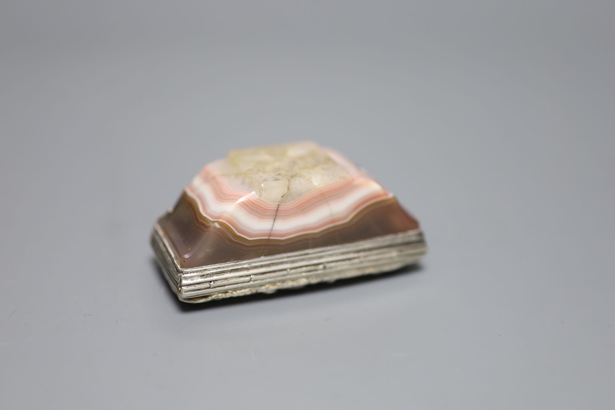 A white metal mounted banded agate snuff box, unmarked, 76mm (agate cracked in several places).
